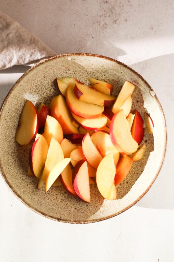 a bowl of sliced peaches on table