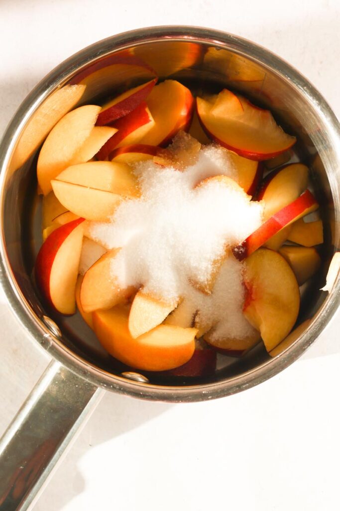 sliced peaches and sugar in pot
