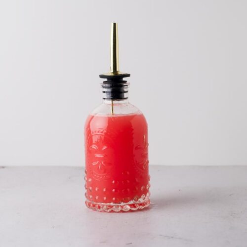 a shot of grapefruit simple syrup on a table with white background
