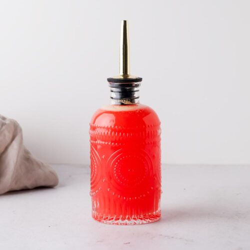 blood orange simple syrup in a glass bottle