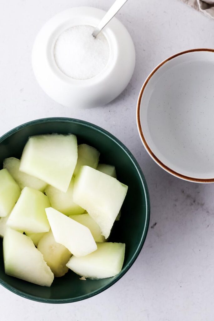 honeydew chunks, water and sugar on a table