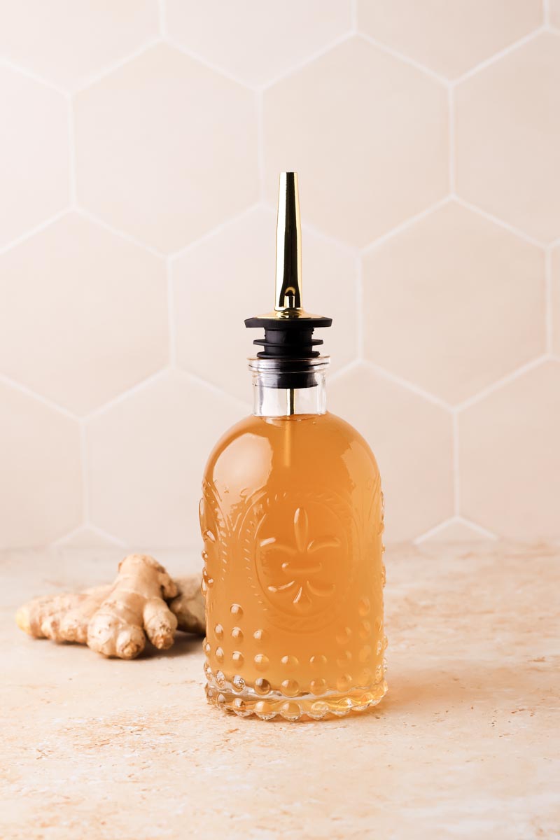 ginger simple syrup in a bottle with small ginger root beside it