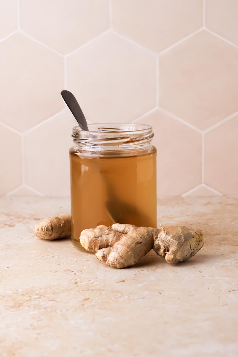 ginger simple syrup in a jar with ginger pieces around it