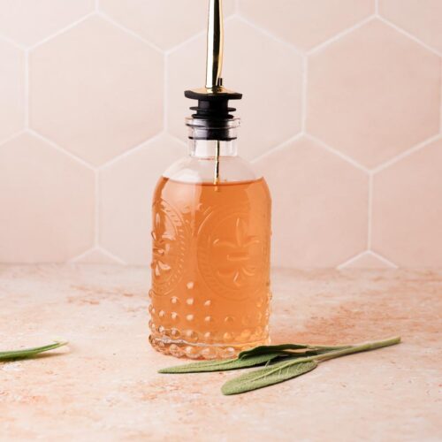 a bottle of sage simple syrup on a table