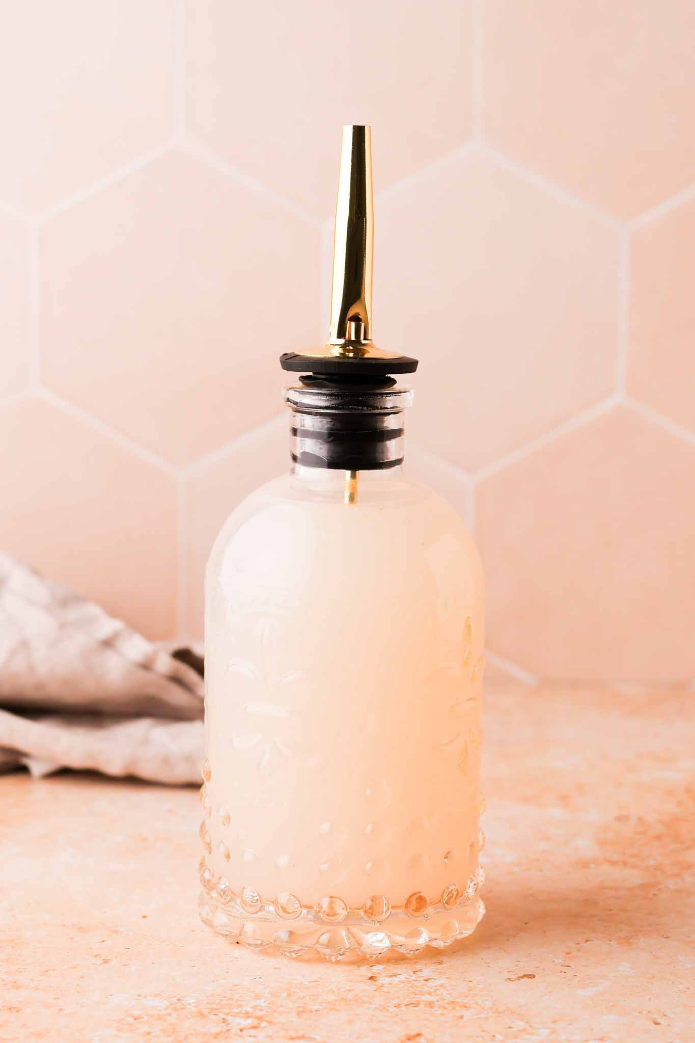 lychee simple syrup in a glass bottle set on a table