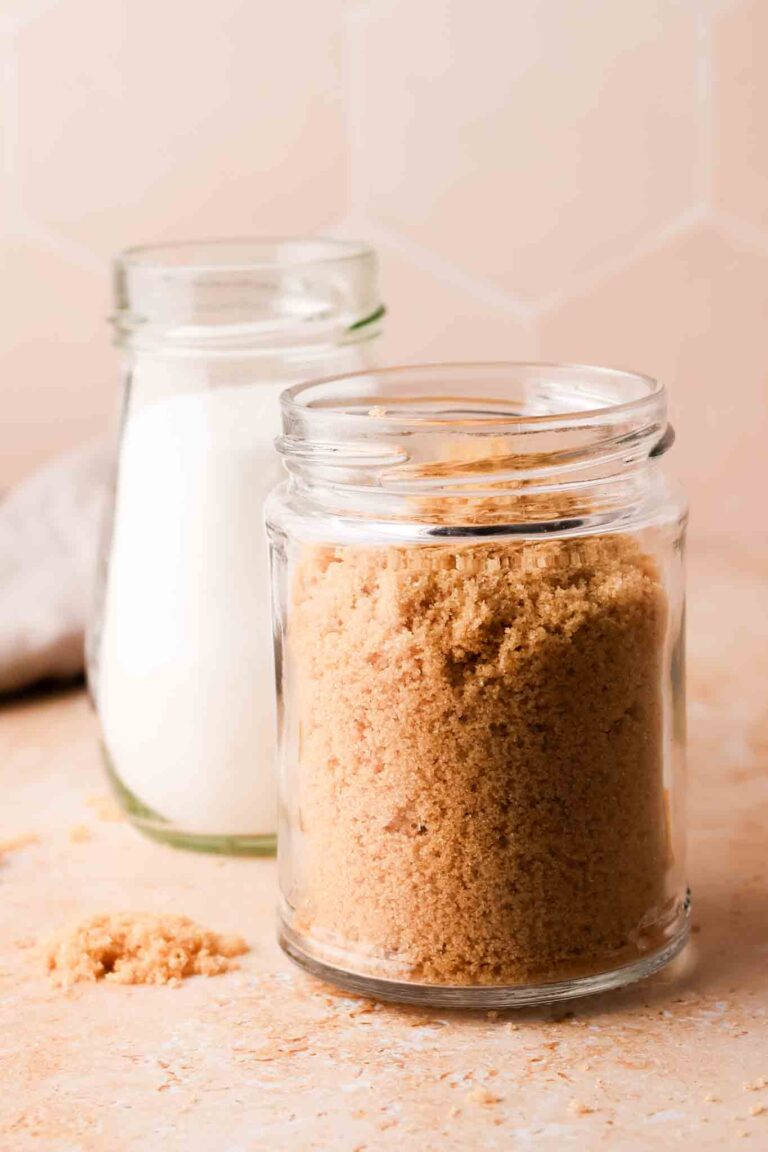 white sugar and brown sugar in a glass jar set on a table