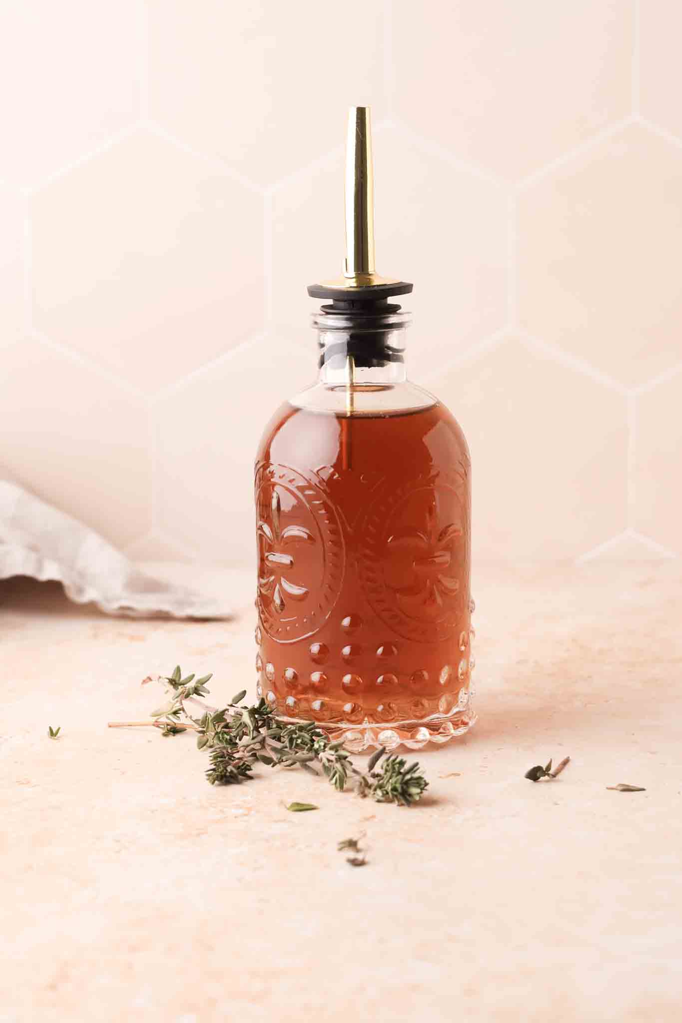 thyme simple syrup in a bottle set on a table