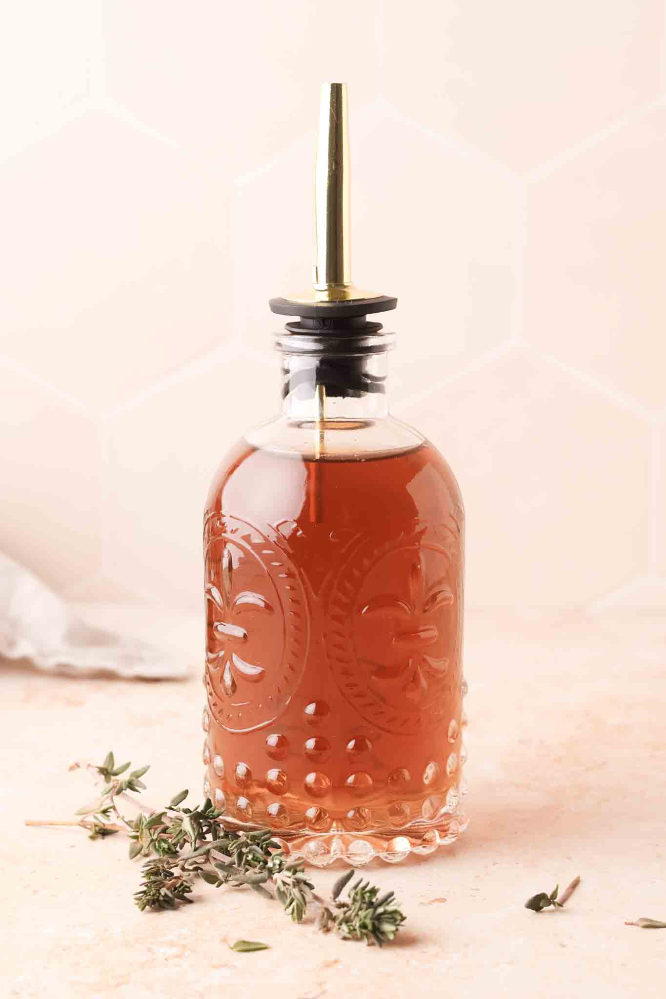 close up of thyme simple syrup in a glass bottle
