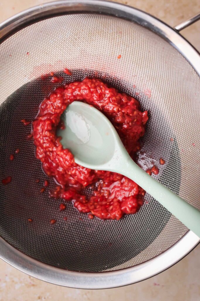 raspberry syrup straining through mesh sieve