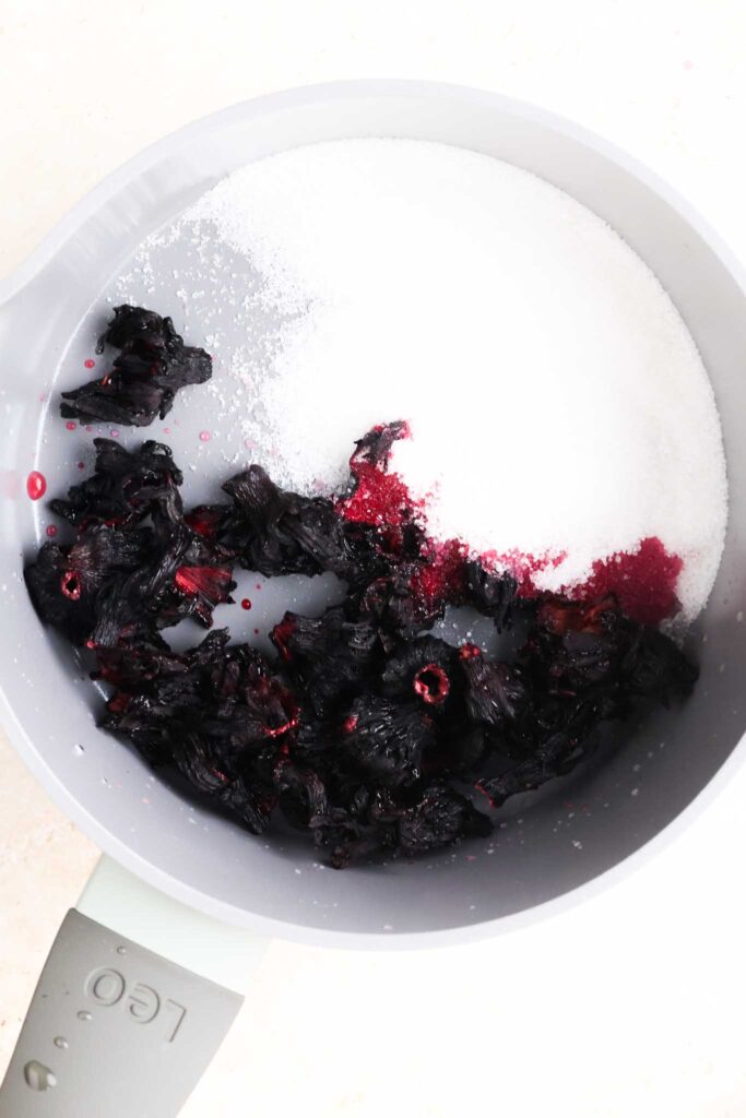sugar and dried hibiscus flowers in saucepan