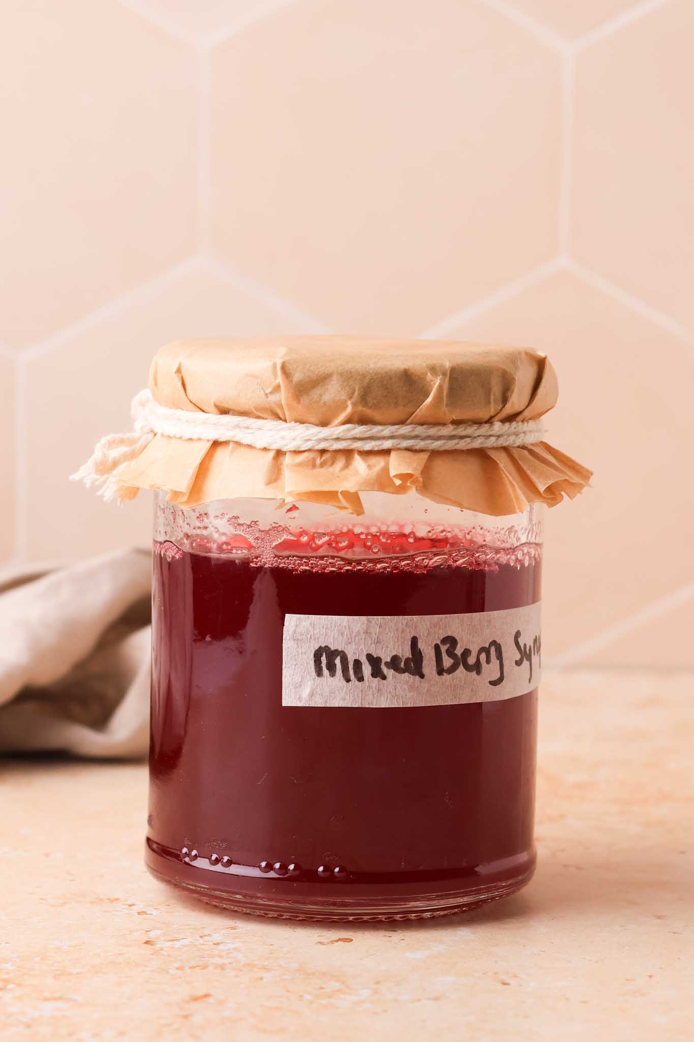 mixed berry simple syrup in a labelled bottle