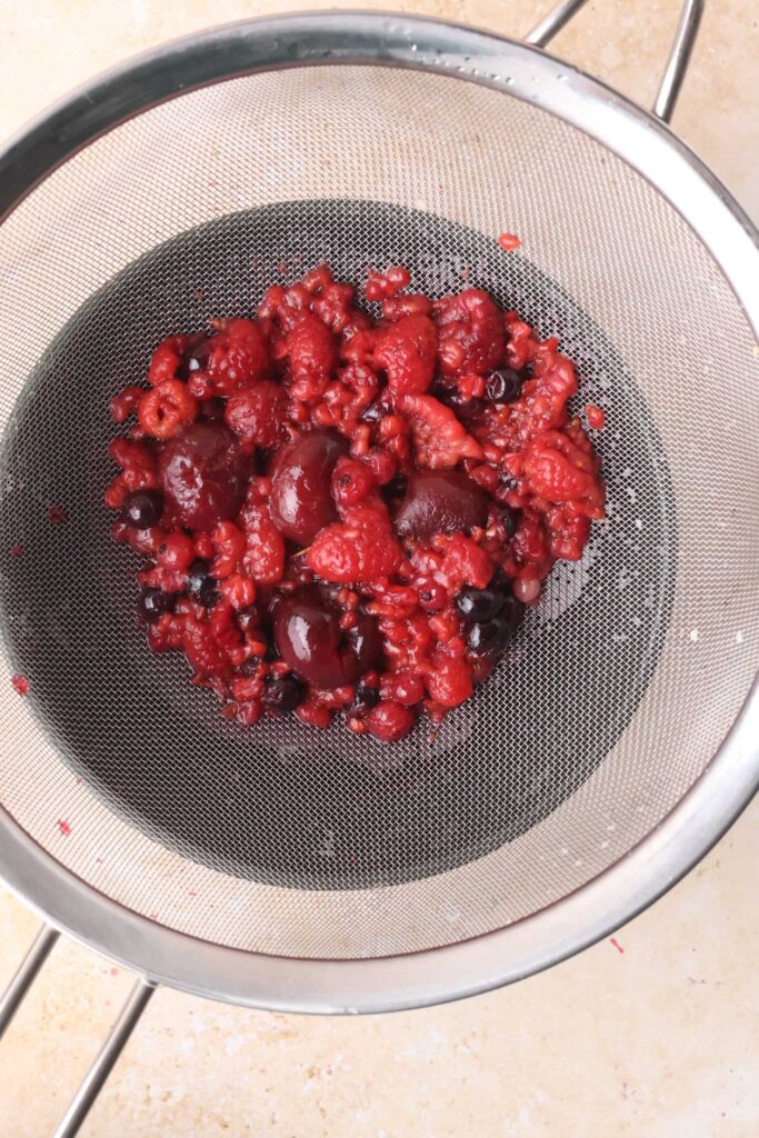 berries straining from syrup in sieve