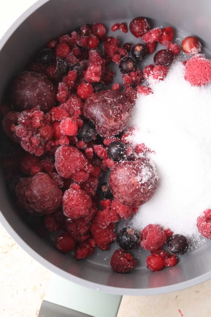 mixed frozen berries and sugar in a saucepan