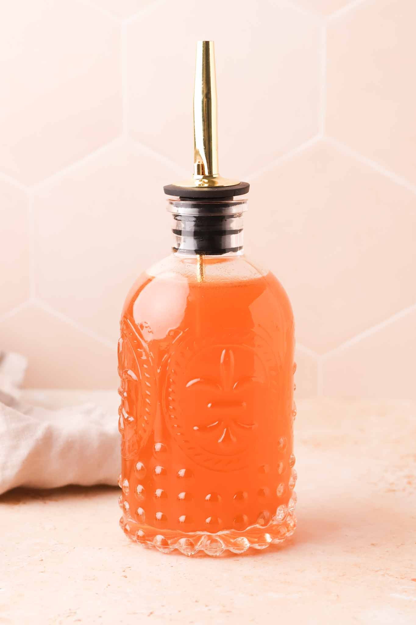 clear bottle filled with apple cider syrup on a simple tabletop