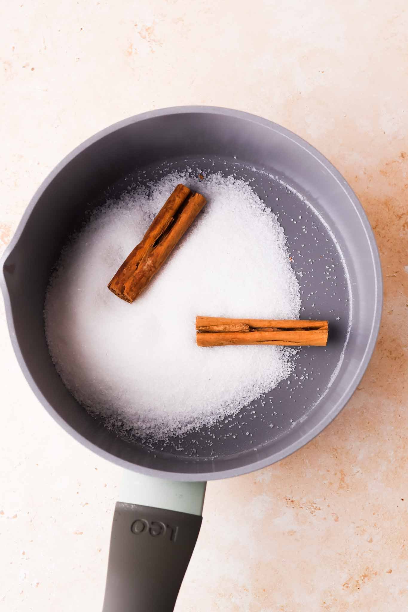 cinnamon sticks and granulated sugar in pan