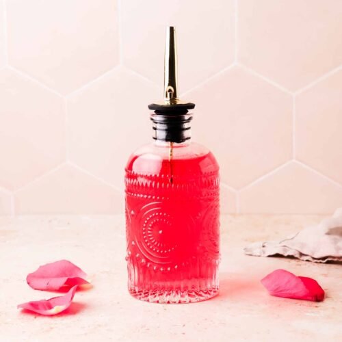 homemade rose simple syrup with rose petals on table