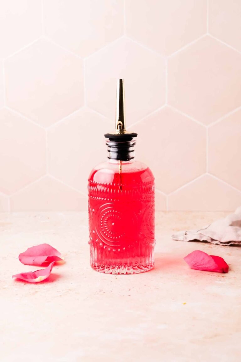 homemade rose simple syrup with rose petals on table
